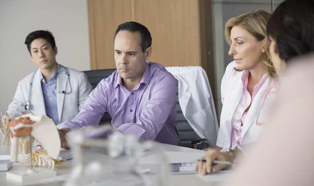 doctors have a discussion around a conference table