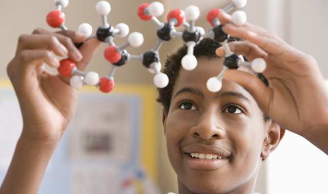 boy holding up model of molecule