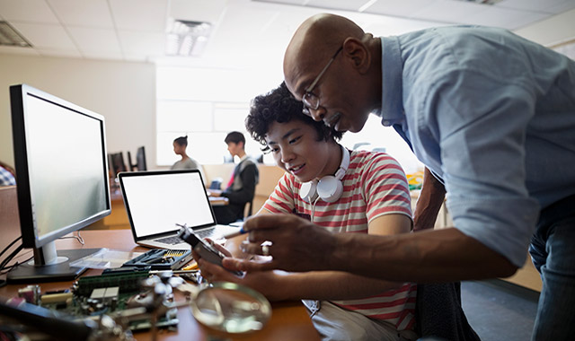 STEM-regional-grants teacher working with a student on a disassembled electronic device