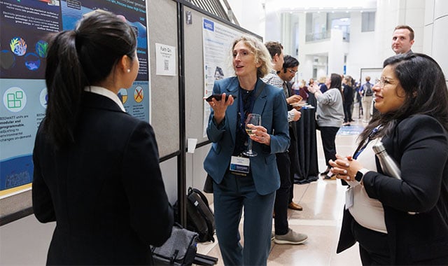 alt=battelle technical fellow Amy Heintz engaging with a poster presenter at the 2024 innovations in climate resilience conference