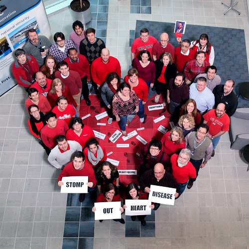 employees wearing red standing in the shape of a heart