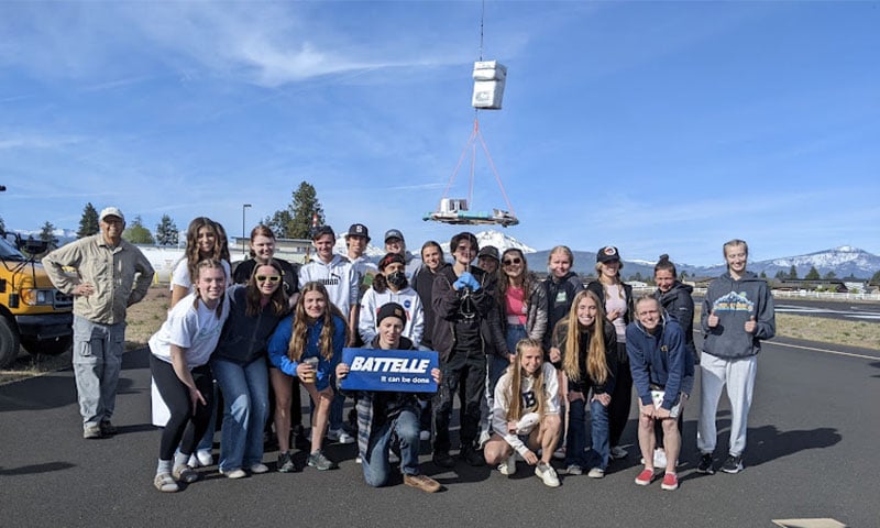 Photo: Students and educators posing with a Battelle sign