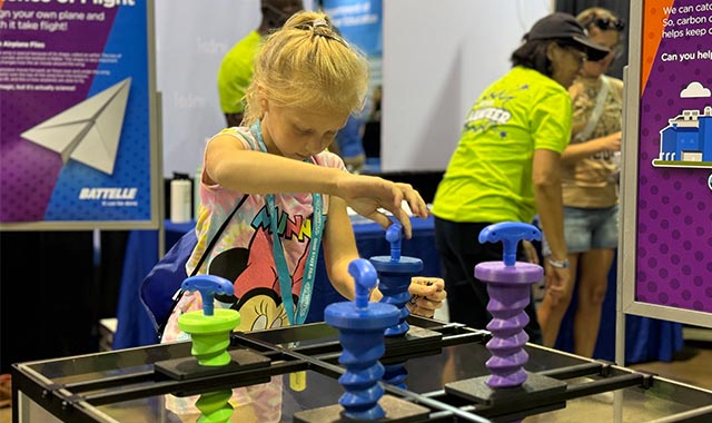 alt=stem student playing with the interactive carbon capture drill at the battelle ohio state fair booth