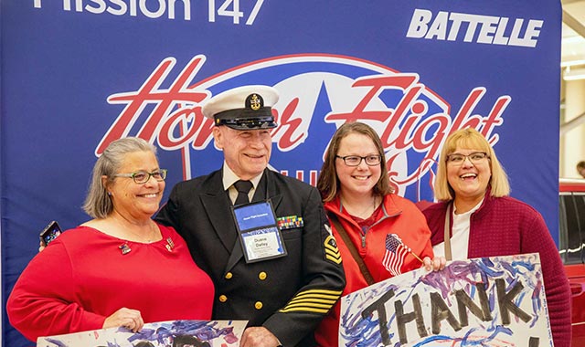 alt= U.S. Navy veteran Duane Dailey with friends and family during the return home from Honor Flight 147