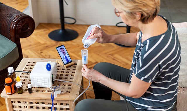 alt = older woman at her home getting assist from her healthcare provider for her hospital at home medical device over video call