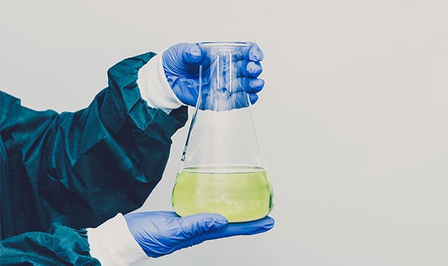 Image: Scientist holding a flask that contains PFAS