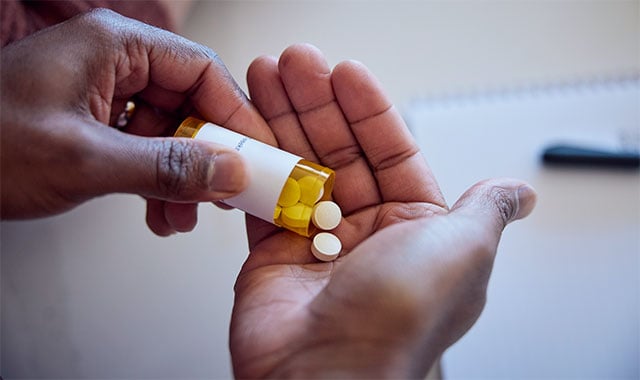 Image: Hands holding and pouring pills from a bottle