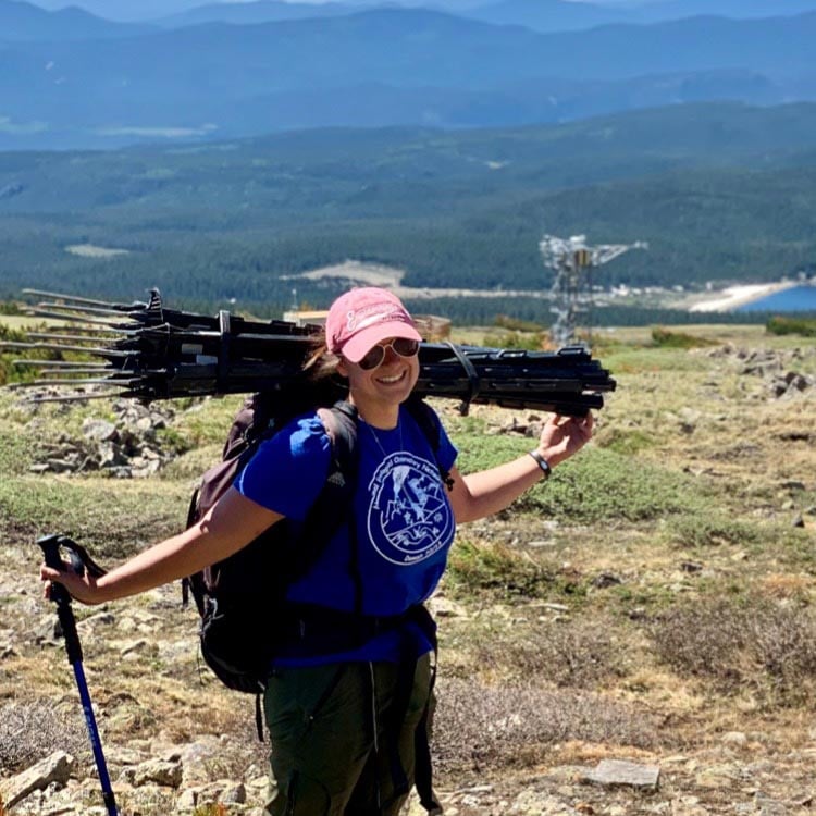 alt= Up at NEON’s Niwot Ridge (NIWO) field site in the Colorado Rockies, Kremidas hauls electric fencing to deter black bears from disturbing NEON pitfall traps, during her last day with Field Science (2021).