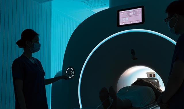 alt=a nurse checking the xray equipment as a women is going through the scanner